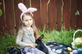 Children play with real rabbit. Laughing child at Easter egg hunt with white pet bunny. Little toddler girl playing with animal in Royalty Free Stock Photo