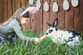 Children play with real rabbit. Laughing child at Easter egg hunt with white pet bunny. Little toddler girl playing with animal in Royalty Free Stock Photo