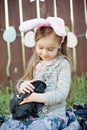 Children play with real rabbit. Laughing child at Easter egg hunt with white pet bunny. Little toddler girl playing with animal in Royalty Free Stock Photo