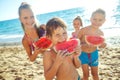 Children play by the sea and eat watermelon.