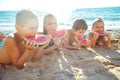 Children play by the sea and eat watermelon.