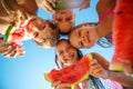 Children play by the sea and eat watermelon.