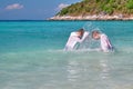 Children play in the sea, splashing each other with water. Two boys in white capes play on the tropical coast in turquoise water. Royalty Free Stock Photo