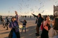 children play with soap bubbles on the main square of the city, happy people enjoy warm sunny evening