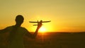 Children play toy airplane. Happy girl runs with a toy airplane on a field in the sunset light. teenager dreams of