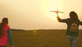 Children play toy airplane. Happy girl sisters run with a toy plane at sunset on the field. The concept of a happy