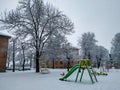 Children playground empty park with slide and swing covered in heavy snow on a cold winter morning during holiday season in suburb Royalty Free Stock Photo