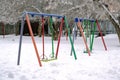 Children Playground with swings, in winter, covered with snow Royalty Free Stock Photo