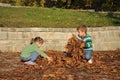 Children playing with autumn fallen leaves in park Royalty Free Stock Photo