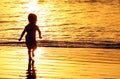 Children playing at the beach in Bali, Indonesia during a golden sunset. Ocean like gold. Royalty Free Stock Photo