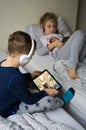 Children playing in bed with their tablets and phones Royalty Free Stock Photo