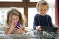 Children playing in bed with their tablets and phones Royalty Free Stock Photo