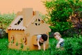 Children are playing in cardboard kid house. Child having fun outdoors. Royalty Free Stock Photo