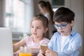 Children playing computer and smartphone while mother busy cooking breakfast Royalty Free Stock Photo