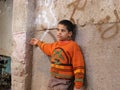 African boy child in the door village in an orange sweater posed against a stone background