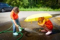 Children playing with garden sprinkler. Brother and sister running and jumping. Summer outdoor water fun in backyard Royalty Free Stock Photo