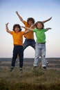 Children playing jumping on summer sunset meadow silhouetted