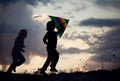 Children playing kite on summer sunset meadow silhouetted Royalty Free Stock Photo