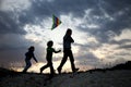 Children playing kite on summer sunset meadow silhouetted Royalty Free Stock Photo