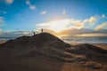 Children playing on a large mound of sand on the beach with sunrise in the background