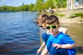 Children playing outdoors in nature: sitting on lake or river shore touching sand in clear water on warm summer or spring day. Royalty Free Stock Photo