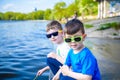 Children playing outdoors in nature: sitting on lake or river shore touching sand in clear water on warm summer or spring day. Royalty Free Stock Photo