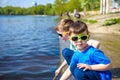 Children playing outdoors in nature: sitting on lake or river shore touching sand in clear water on warm summer or spring day Royalty Free Stock Photo