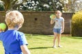 Children playing outside a brother and sister play a ball game in a garden Royalty Free Stock Photo