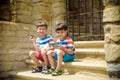 The children playing on the ruins of ancient building with metal gate an archaeological site of an ancient city. Two boys sitting