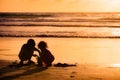 Children playing with sand by the sea at sunset in Tobago Royalty Free Stock Photo