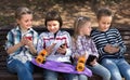 Children playing in smartphones on street bench in park Royalty Free Stock Photo