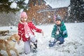 Children playing on snow with dog in winter holiday