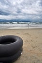 Children playing on a stormy evening at the beach with dramatic clouds and waves. With life jackets and swim rings in Royalty Free Stock Photo