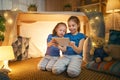 Children are playing with tablet in tent