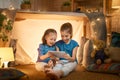 Children are playing with tablet in tent