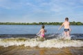 Children playing in the water by the river.  Boy and girl jumping on the waves.  Back view Royalty Free Stock Photo