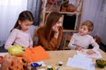 Children prepare Halloween decorations, paint and carve. A loving mother next to them at the table helps them with this Royalty Free Stock Photo