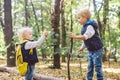 Children preschoolers Caucasian brother and sister take pictures of each other on mobile phone camera in forest park