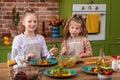 Children In Pyjamas Making Pancakes In Kitchen At Home Following Recipe On Digital Tablet Royalty Free Stock Photo