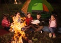 Children reading book with flashlight outdoors. Summer camp Royalty Free Stock Photo