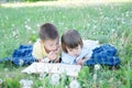 Children reading book lying on stomach outdoor among dandelion in park, cute children education and development. Back to school co Royalty Free Stock Photo