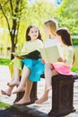 Children reading books at park. Girls sitting against trees and lake outdoor Royalty Free Stock Photo