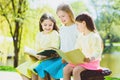 Children reading books at park. Girls sitting against trees and lake outdoor Royalty Free Stock Photo