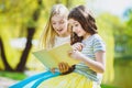 Children reading books at park. Girls sitting against trees and lake outdoor Royalty Free Stock Photo