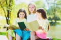 Children reading books at park. Girls sitting against trees and lake outdoor Royalty Free Stock Photo