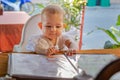 Children  reading chooses and studies the menu in the restaurant. Infant girl is sitting on a baby`s high chair in a street cafe Royalty Free Stock Photo