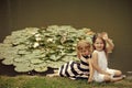 Children rest at the lake. Girl wave hand at pond with water lily flowers