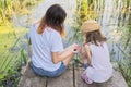 Children resting near the water on summer day, playing with water snails, back view Royalty Free Stock Photo