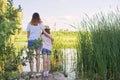 Children resting near the water on sunny summer day, back view Royalty Free Stock Photo