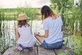 Children resting near the water on summer day, playing with water snails, back view Royalty Free Stock Photo